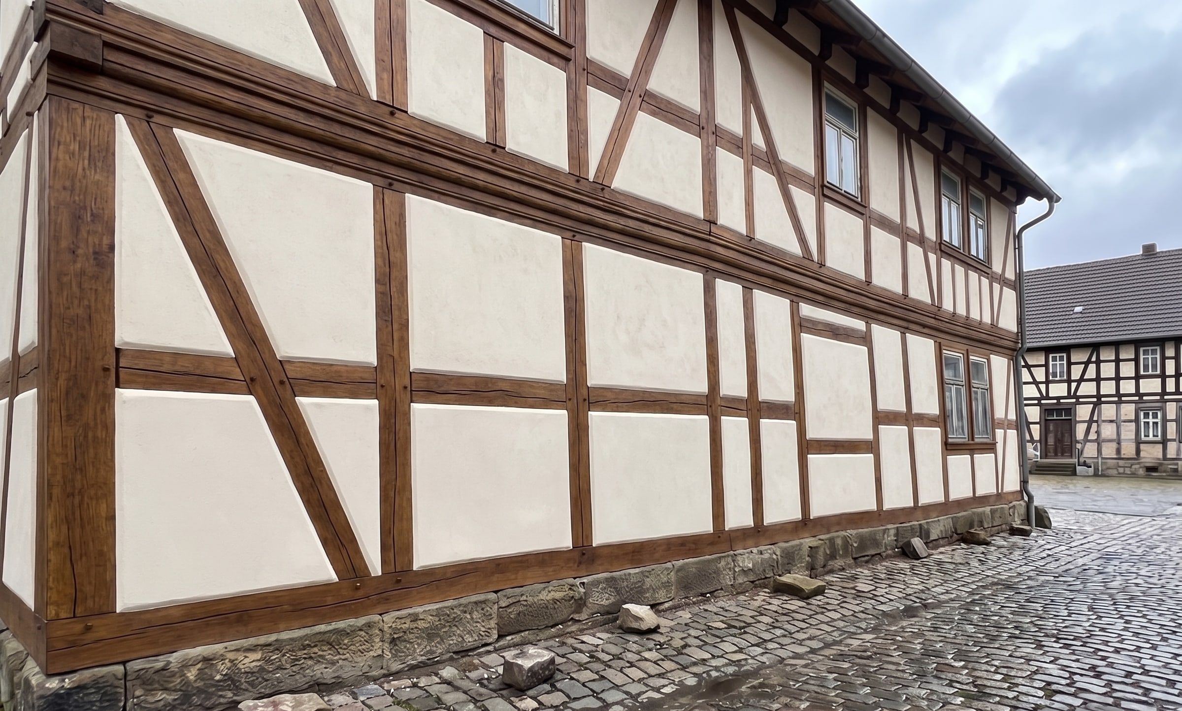Dieselbe Fachwerkfassade mit instandgesetzten, frisch verputzten Gefachen und geöltem Holzwerk