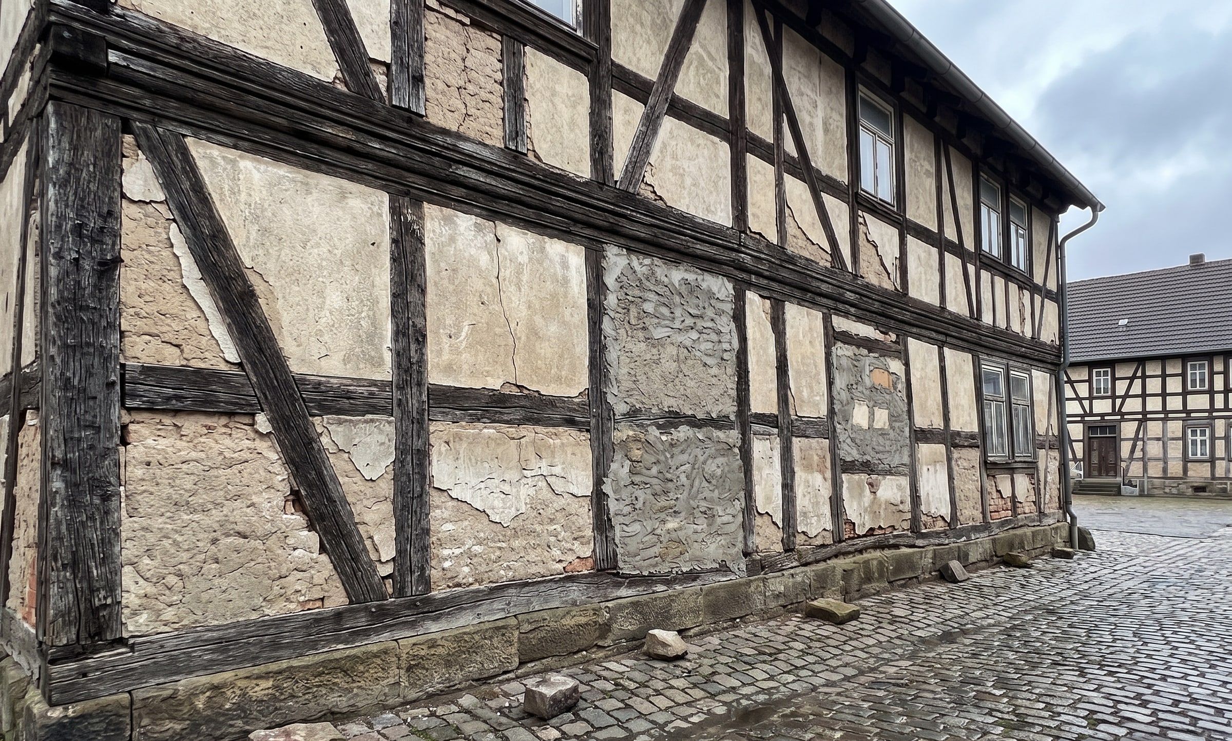 Fachwerkfassade mit schadhaften Gefachen, Rissen und abgeplatztem Putz