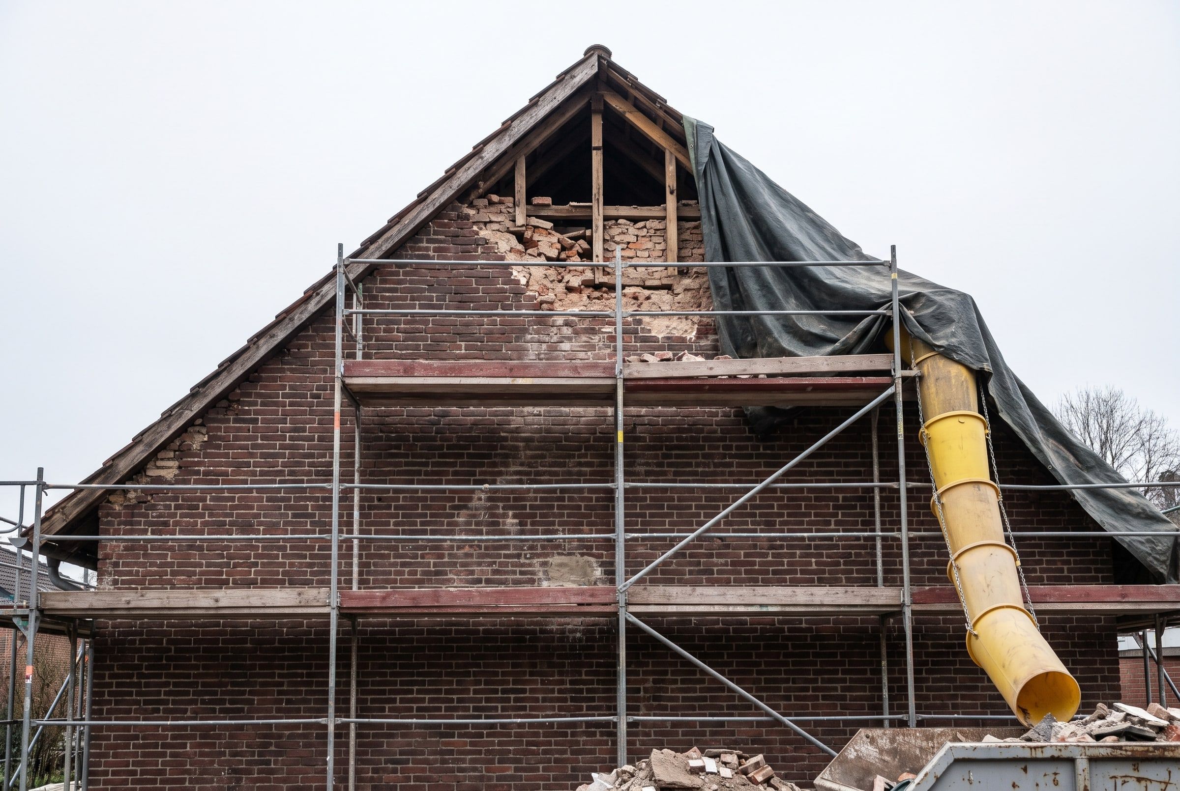Eingerüsteter Altbau-Giebel mit teilweise abgetragenem, geschädigtem Mauerwerk