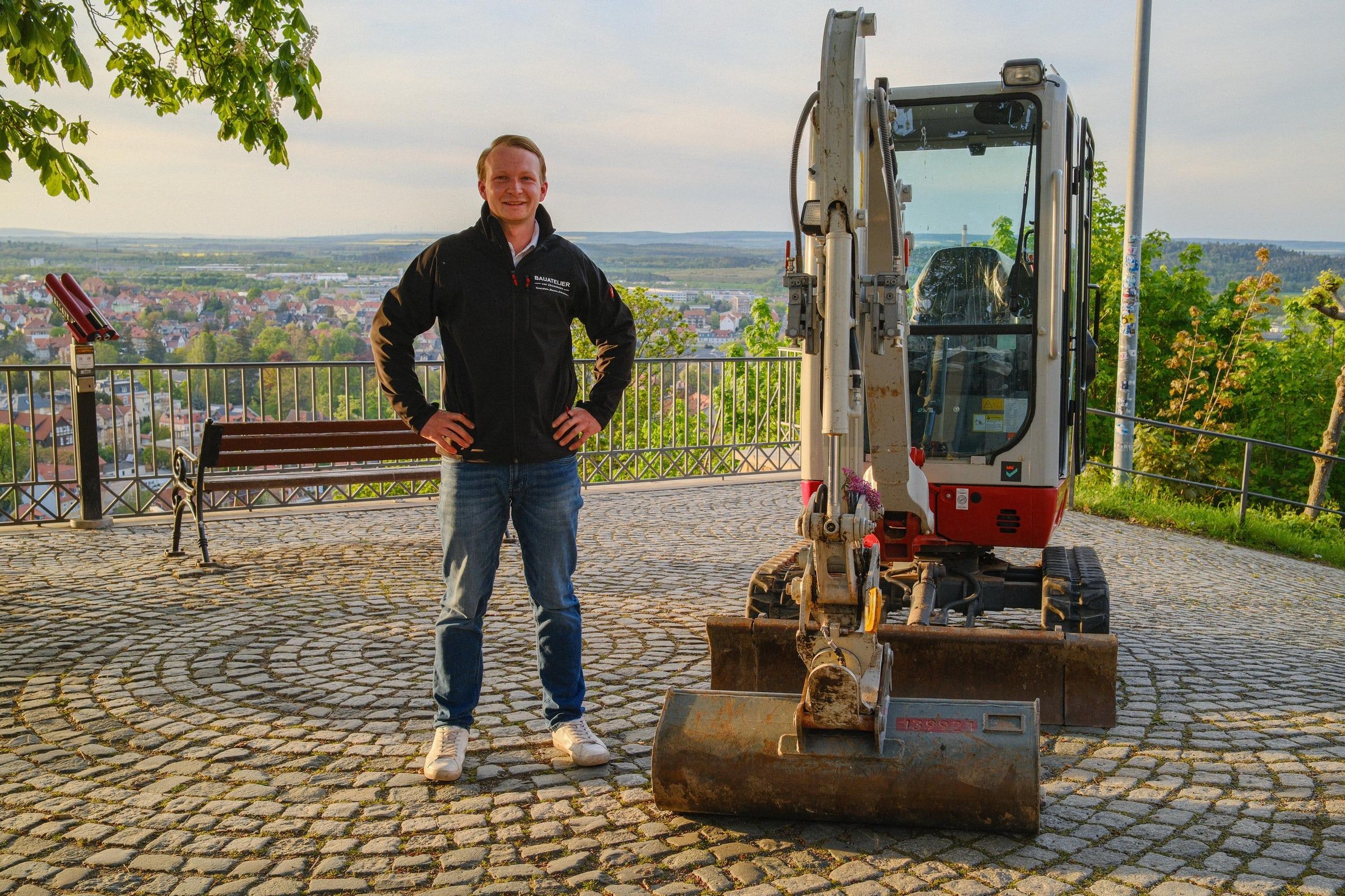 Maurermeister von Zschinsky vor einem Minibagger mit Blick über die Harzregion bei Blankenburg