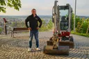 Maurermeister von Zschinsky vor einem Minibagger mit Blick über die Harzregion bei Blankenburg