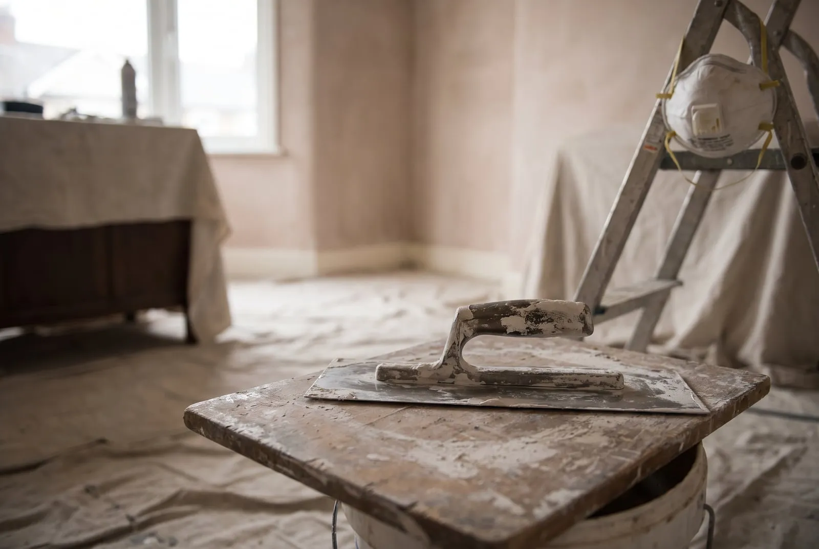 Frisch verputzte Innenwand mit Kelle, Traufel und Leiter
